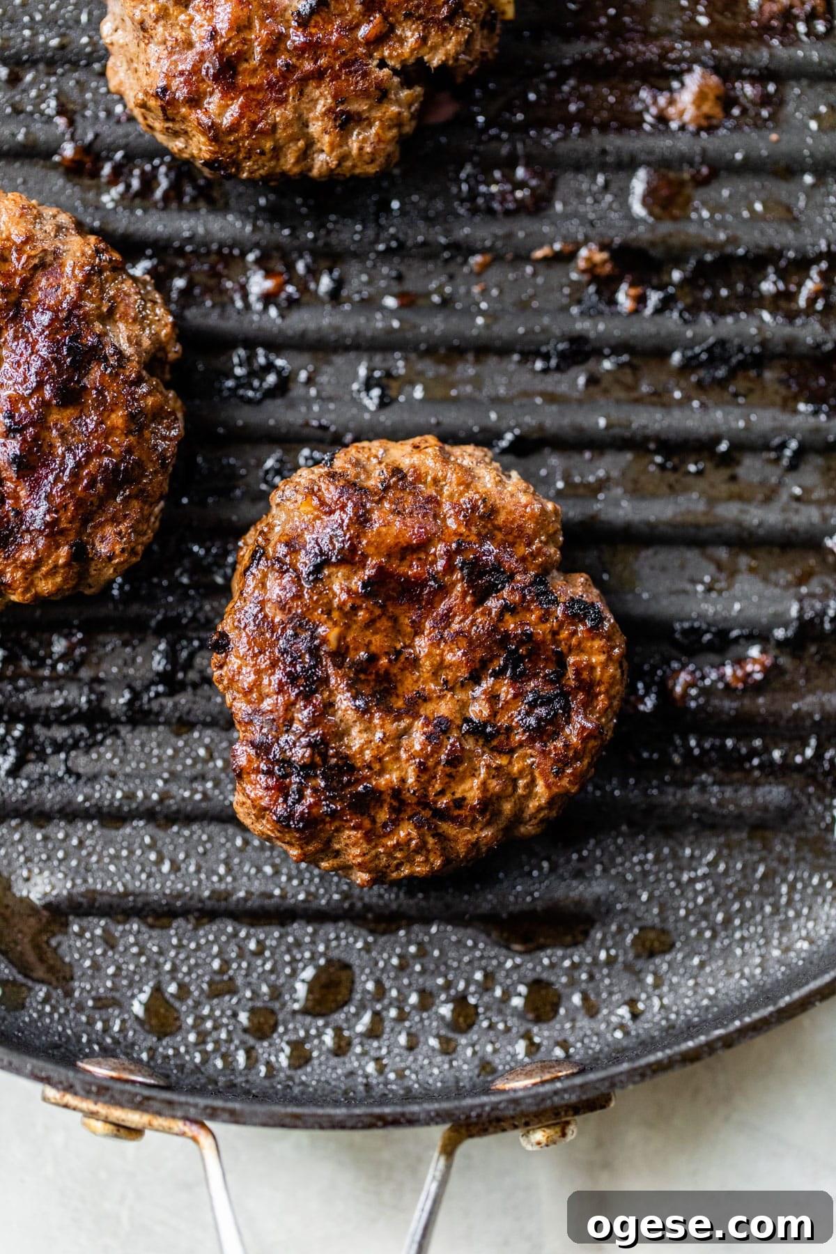 Juicy Grilled Bison Burgers with Smoky Onion Jam 4 burger being grilled on a grill pan