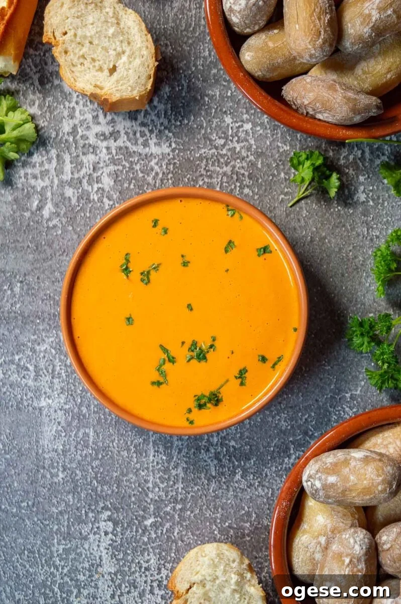 A bowl with thick orange dip surrounded by sliced baguette and salt encrusted wrinkly potatoes.