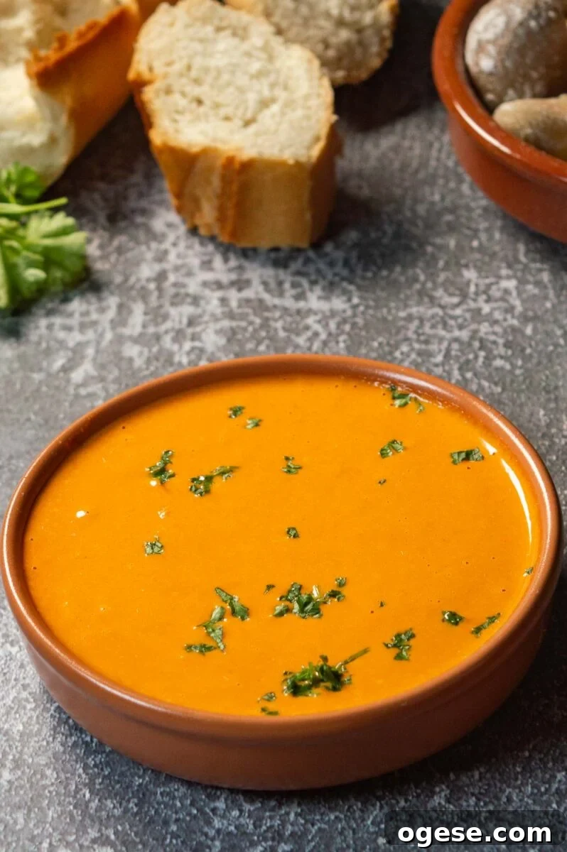 A terracotta dish with thick orange sauce in it on a grey background.
