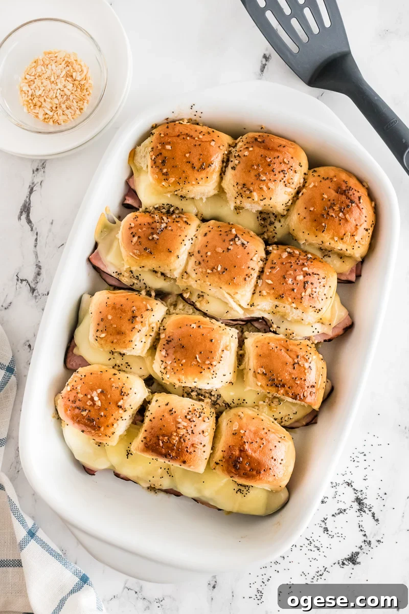 Ultimate Cheesy Ham and Melted Cheese Sliders Recipe 8 Poppyseed and butter mixture is spread on top of the sliders.