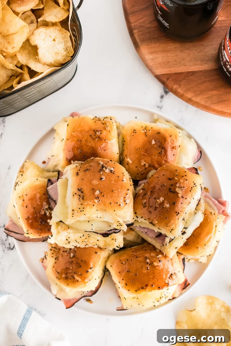 Ultimate Cheesy Ham and Melted Cheese Sliders Recipe 4 Overhead image of ham and cheese sliders on Hawaiian rolls on a plate.