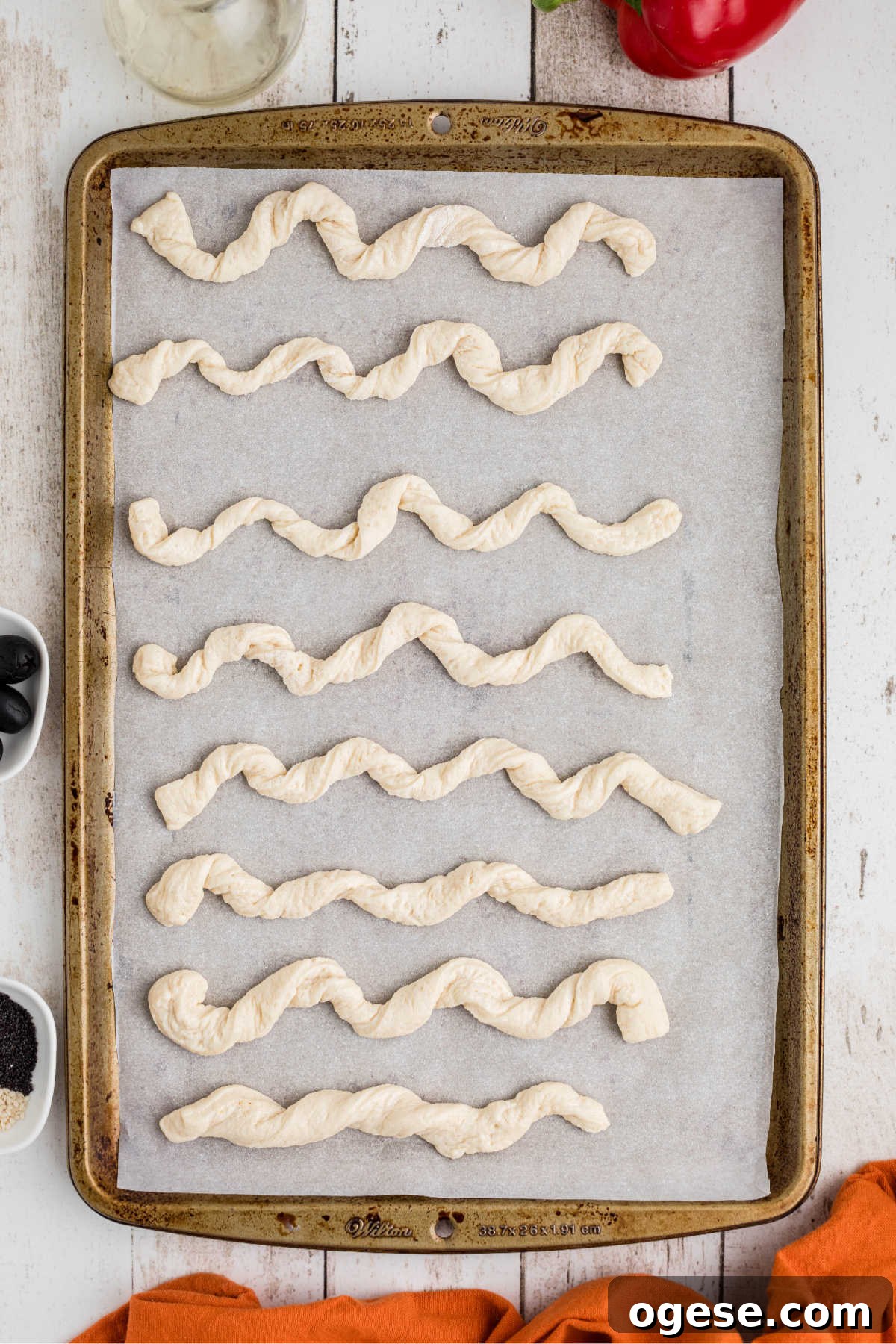 Crispy Breadstick Rattlers: Spicy Sausage-Stuffed Appetizers 5 Rolled up pizza dough strands on a baking sheet.