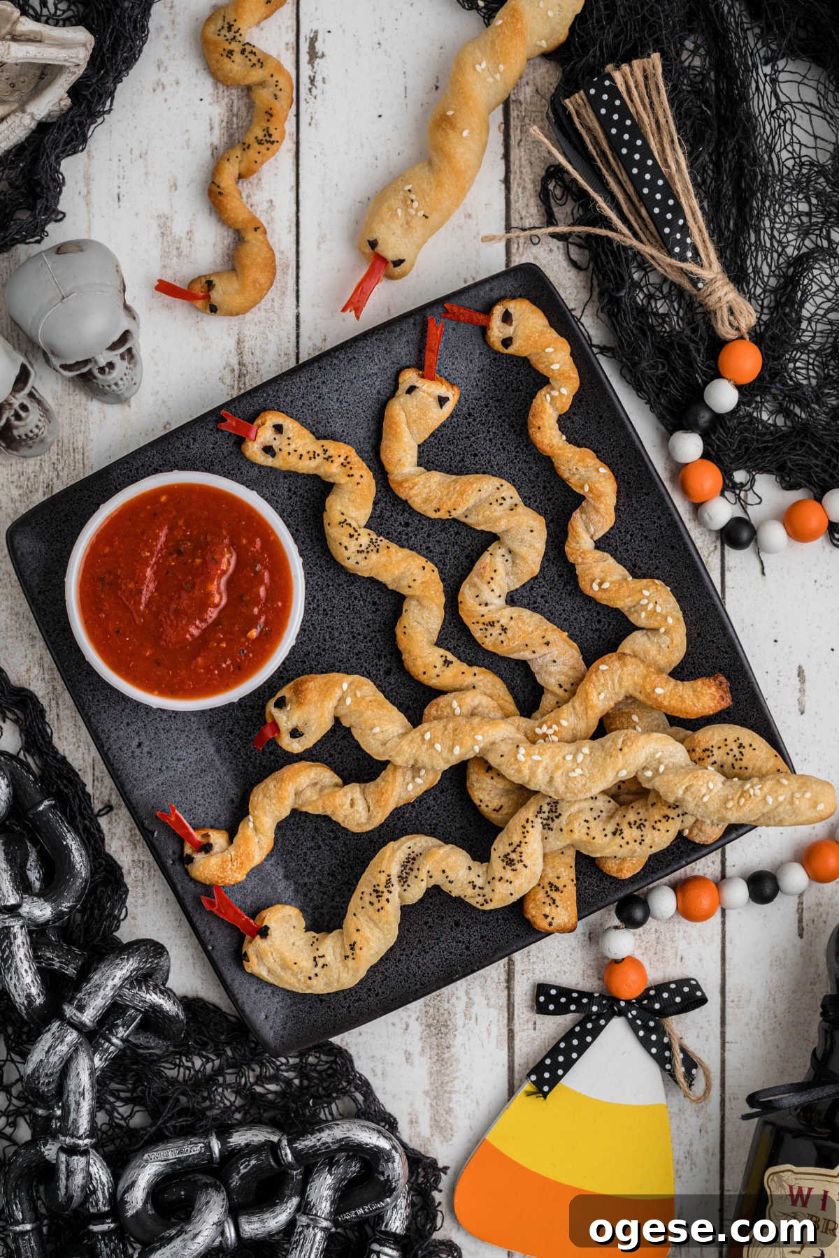 Crispy Breadstick Rattlers: Spicy Sausage-Stuffed Appetizers 9 Breadstick rattlers on a plate with Halloween decorations all around.