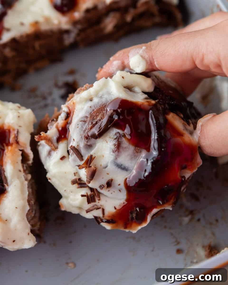 Cherry chocolate cinnamon roll pulled apart with mascarpone frosting and cherry sauce