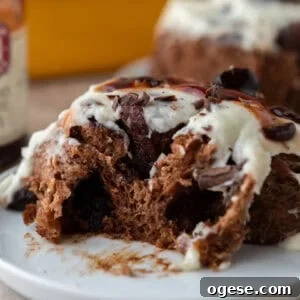 Soft Black Forest cinnamon roll with chocolate dough, cherry filling, and vanilla mascarpone frosting on a plate