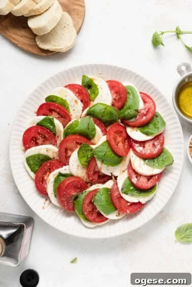Classic Caprese Salad Recipe: Fresh Mozzarella, Tomatoes & Basil 13 Caprese salad on a plate with fresh basil.