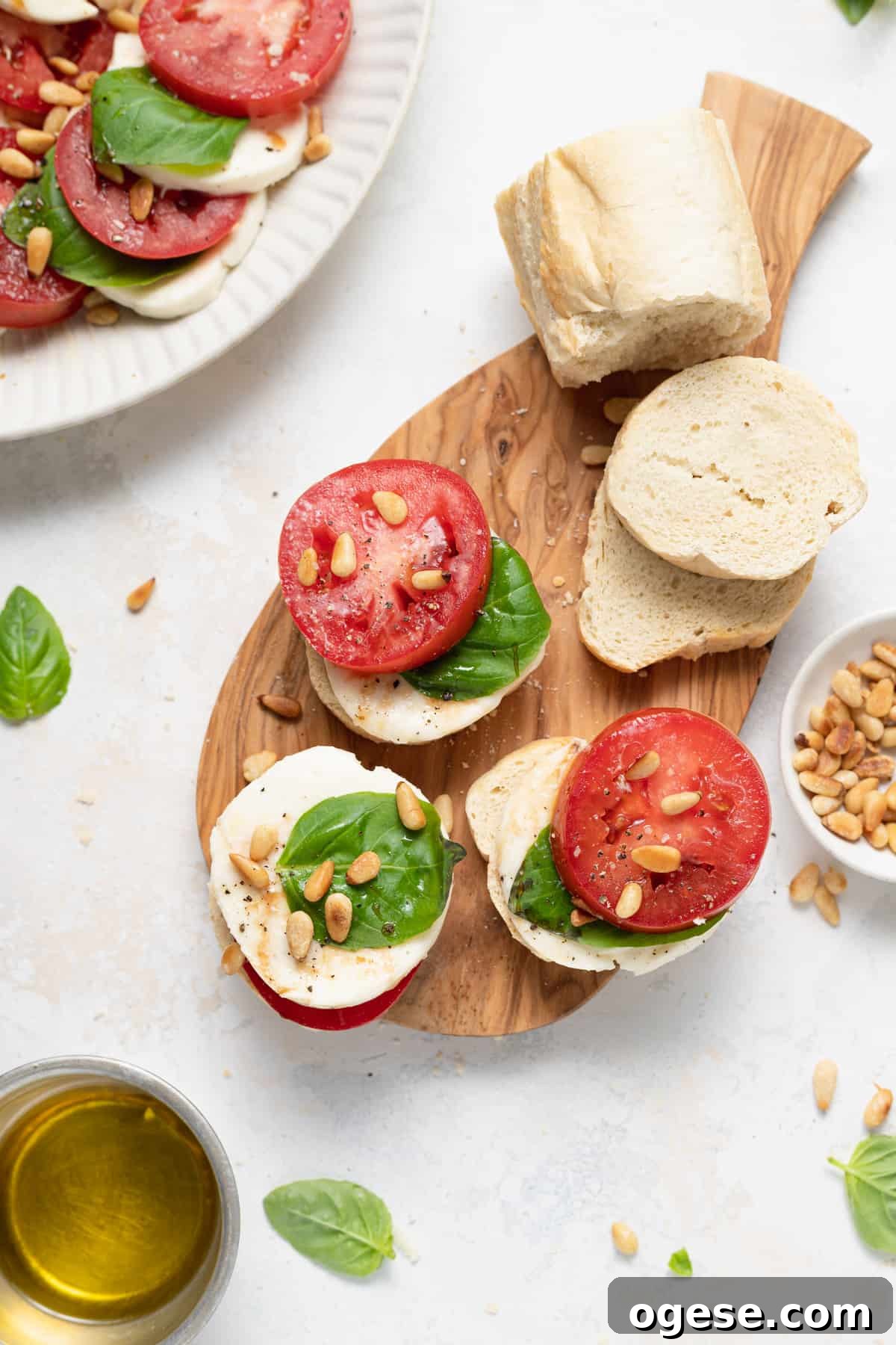Classic Caprese Salad Recipe: Fresh Mozzarella, Tomatoes & Basil 5 Caprese salad on a cutting board with slices of bread.