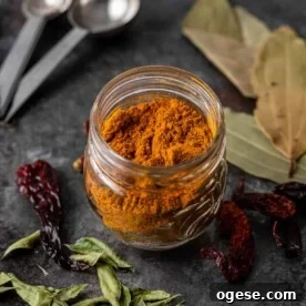 madras curry powder in glass jar on table with drie dchili and leaves