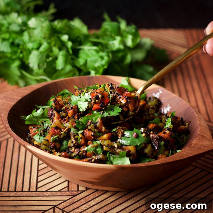 Someone lifting a spoonful of almond salsa from a wood bowl that's filled with the salsa.