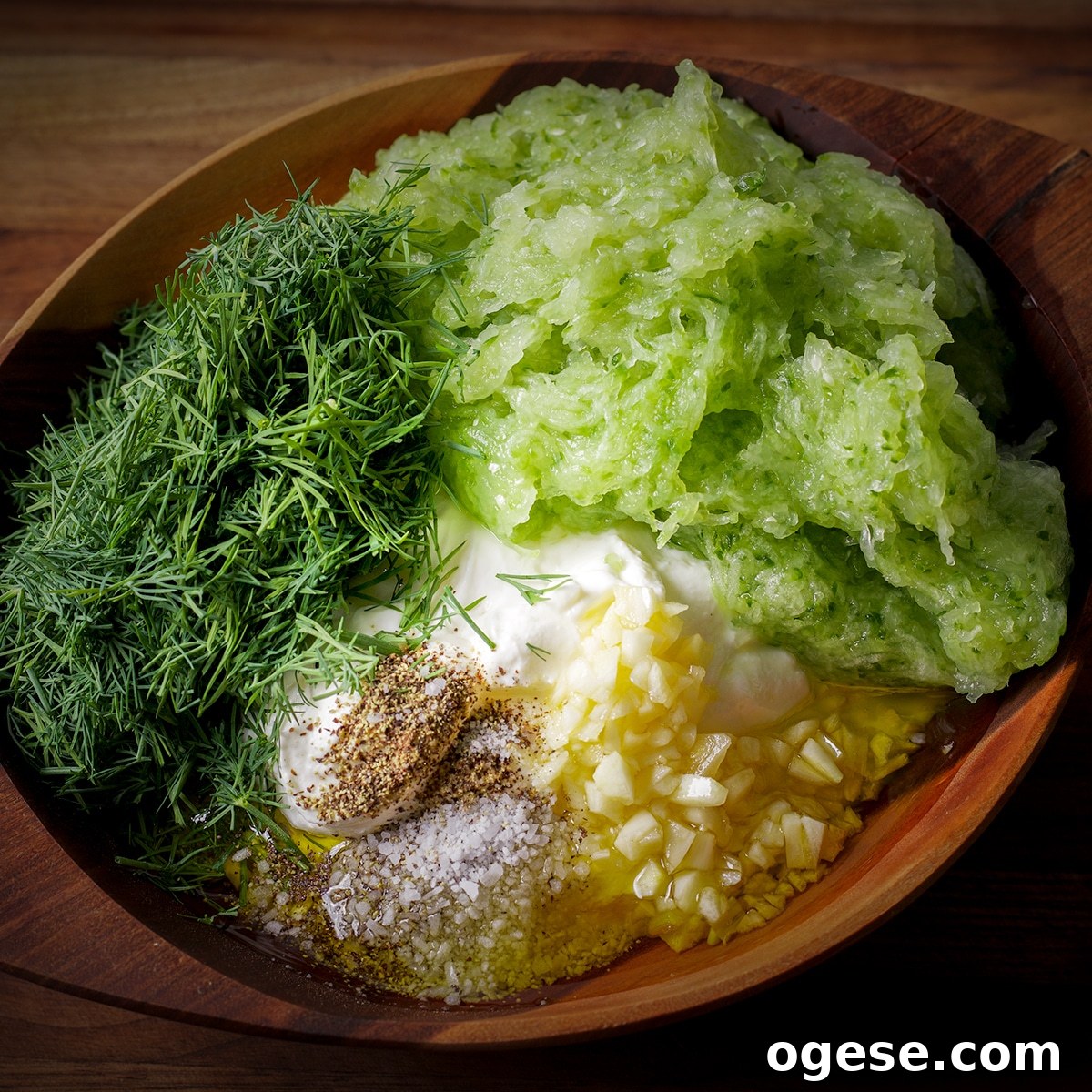 Traditional and Vegan Tzatziki: Two Authentic Recipes You’ll Love 6 A wood bowl containing all the ingredients to make tzatziki sauce before the sauce is mixed.