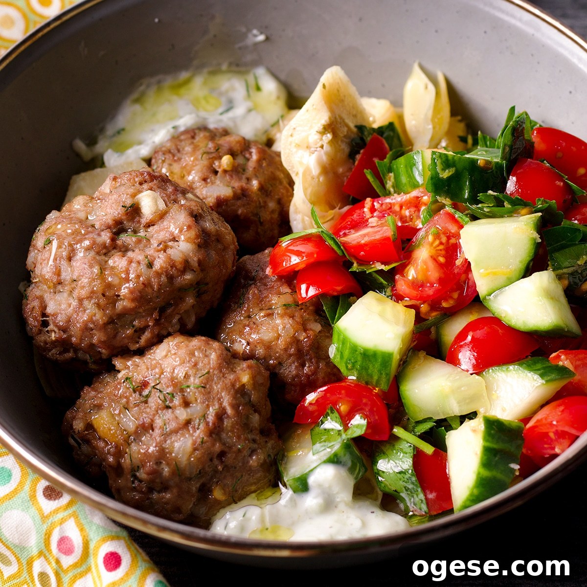 Traditional and Vegan Tzatziki: Two Authentic Recipes You’ll Love 10 A bowl containing Greek meatballs and tzatziki sauce, and tomato and cucumber salad.
