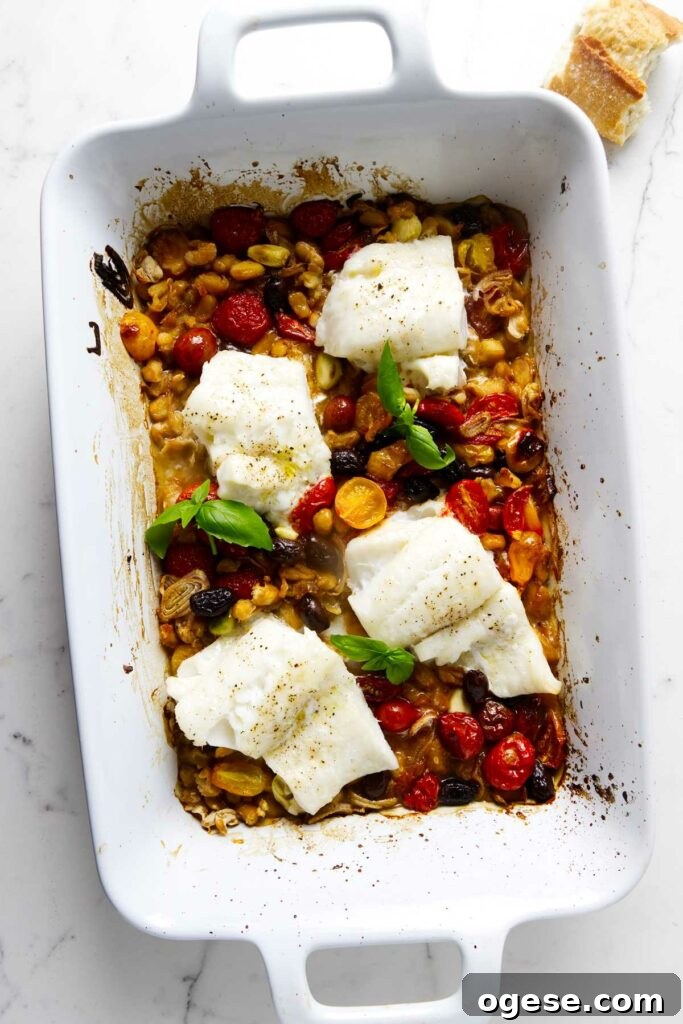 Baked cod in a ceramic dish with tomatoes, olives, and beans.
