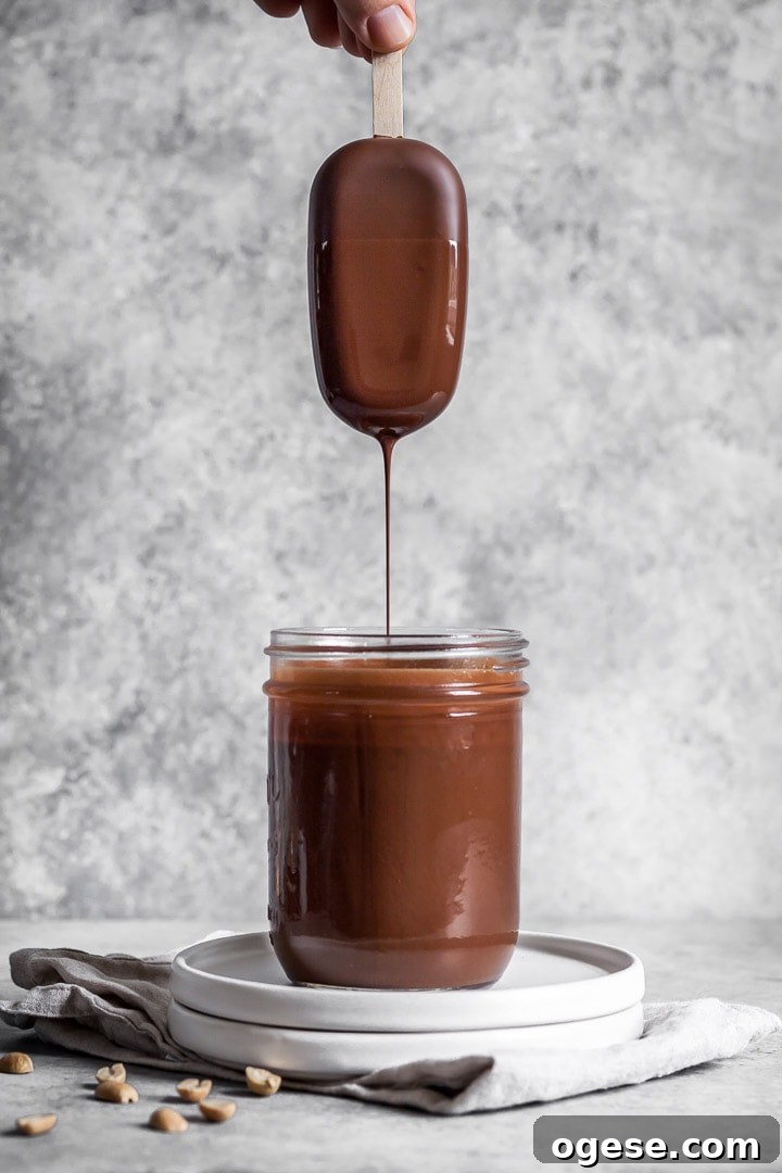 Hand dipping peanut butter ice cream bar into chocolate
