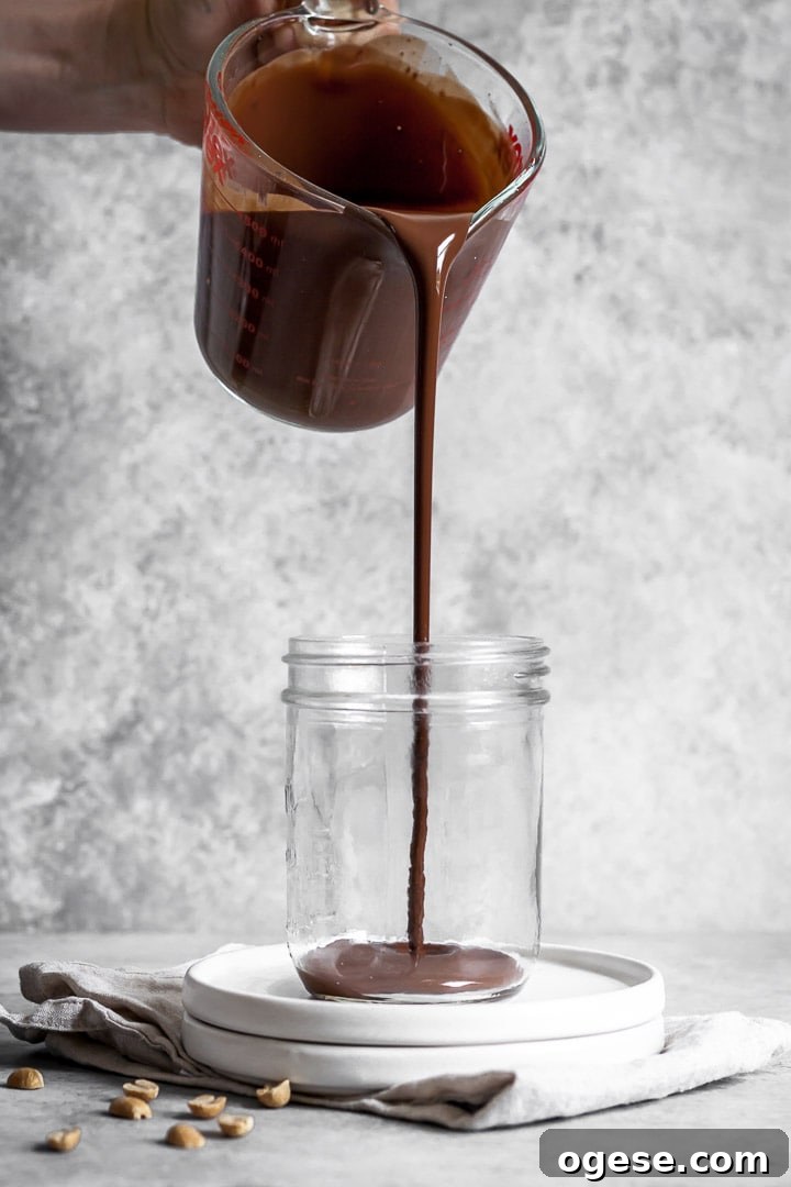 Melted chocolate being poured into a jar with a grey background behind