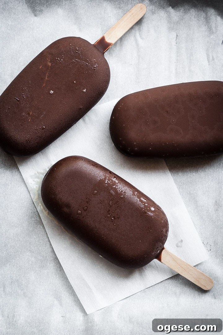 Three chocolate dipped ice cream bars on parchment paper
