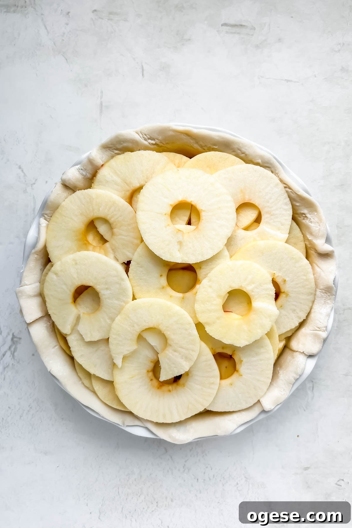 Round apple slices stacked inside store-bought pie crust.