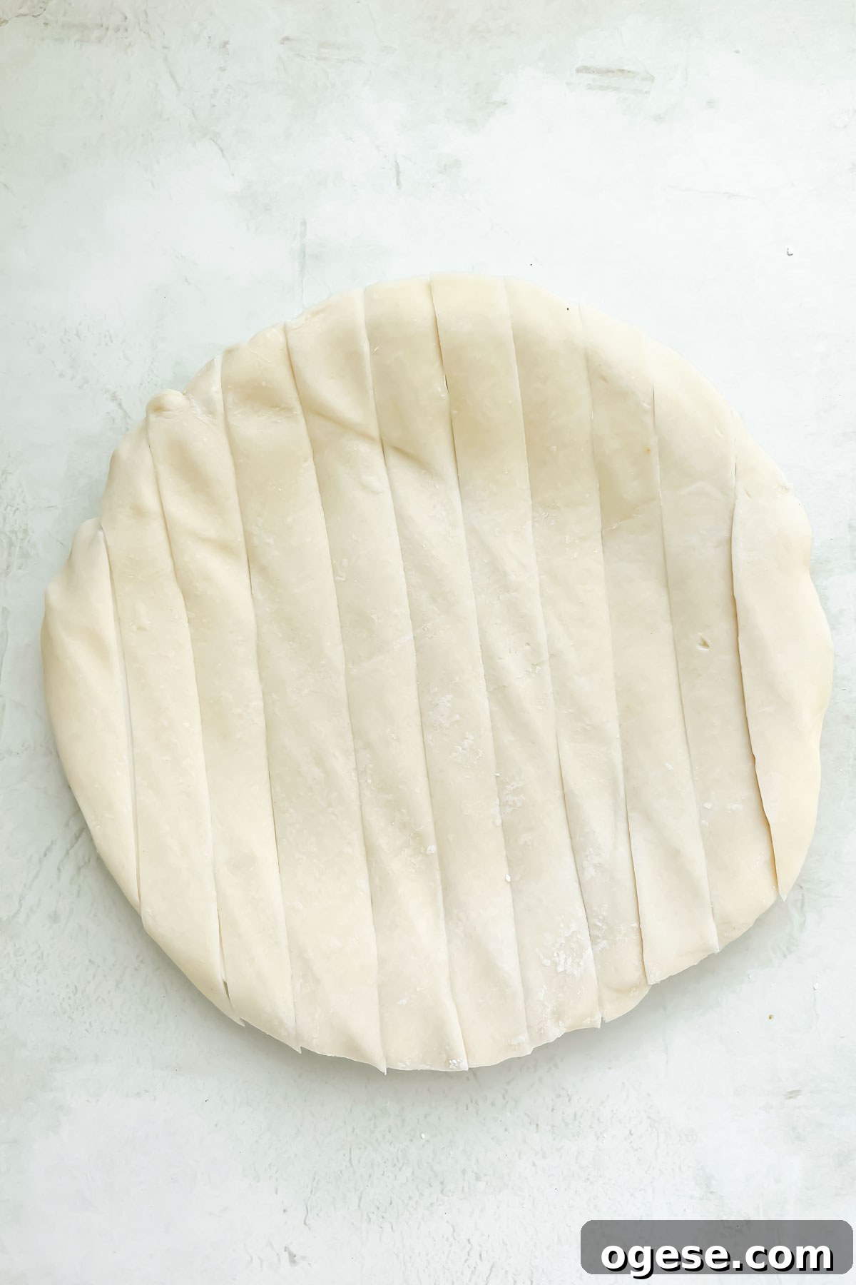 store-bought pie crust for a easy apple pie cut into vertical strips on a neutral backdrop.