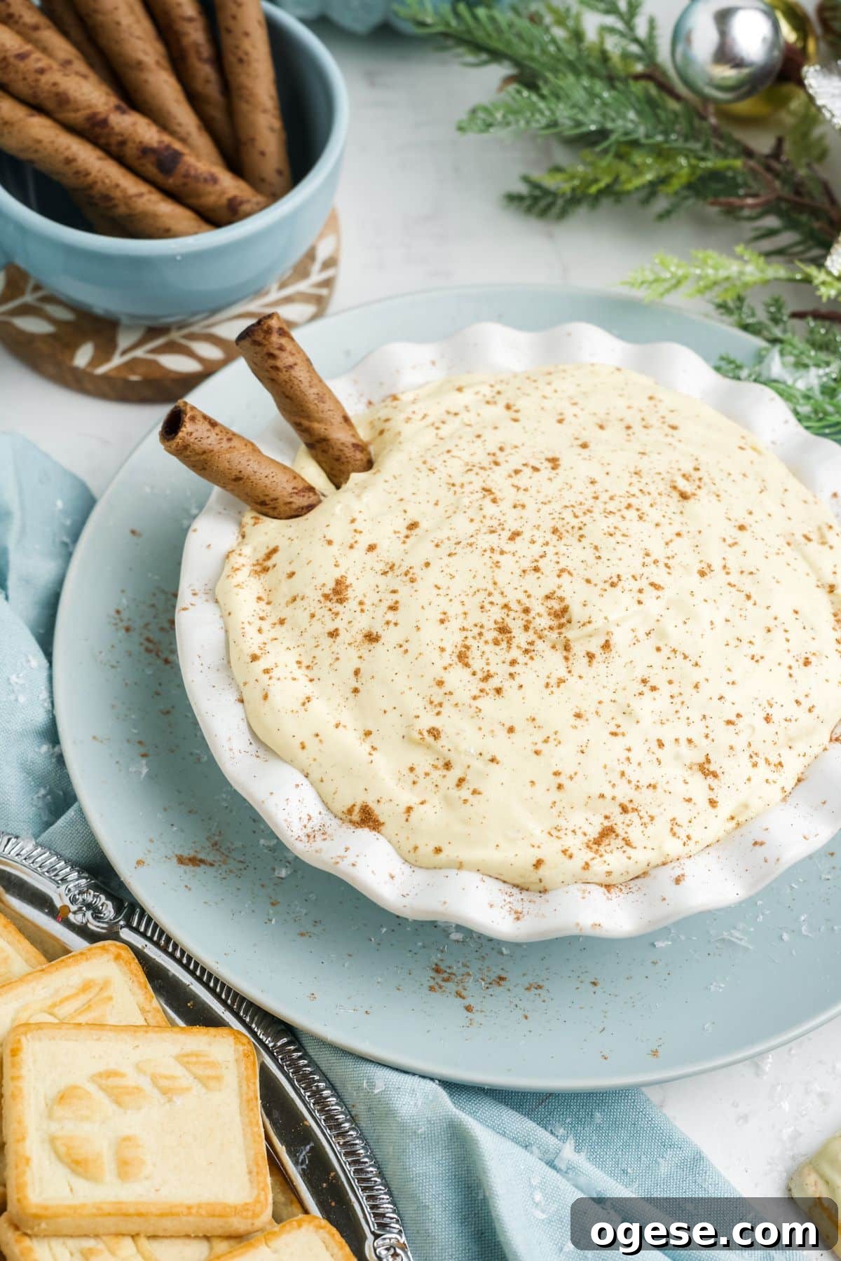 Eggnog dip in a bowl on the table garnished with a sprinkle of cinnamon and whole sticks.