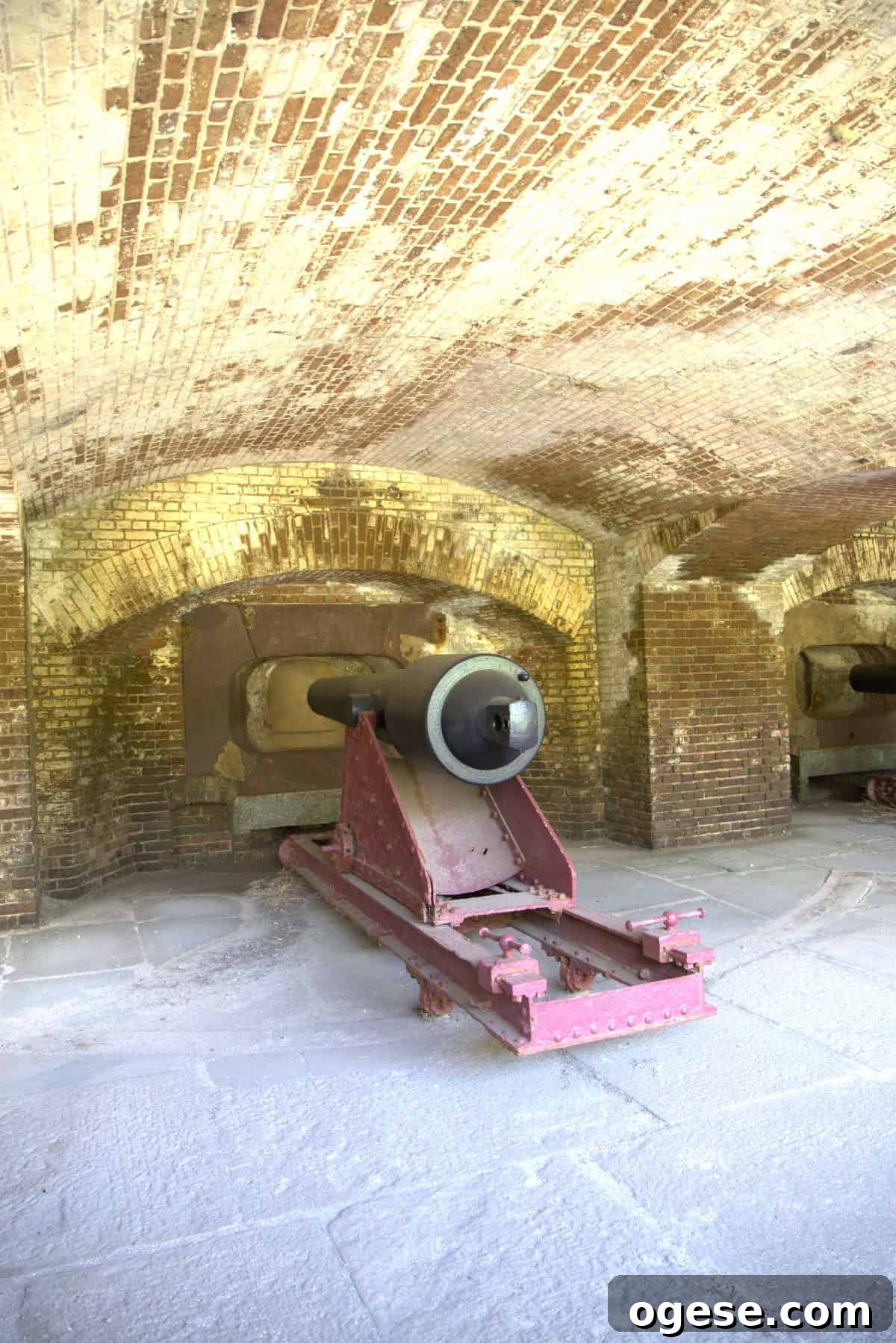 Charleston Travel Guide: Top Attractions, Food & Historic Tours 3 Large historic cannon mounted on a red metal carriage inside a brick-walled fort with arched ceilings, as featured in many Charleston travel guide recommendations.