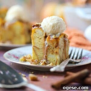 A serving of pumpkin bread pudding with salted caramel sauce and vanilla ice cream on a white dessert plate with a silver fork.