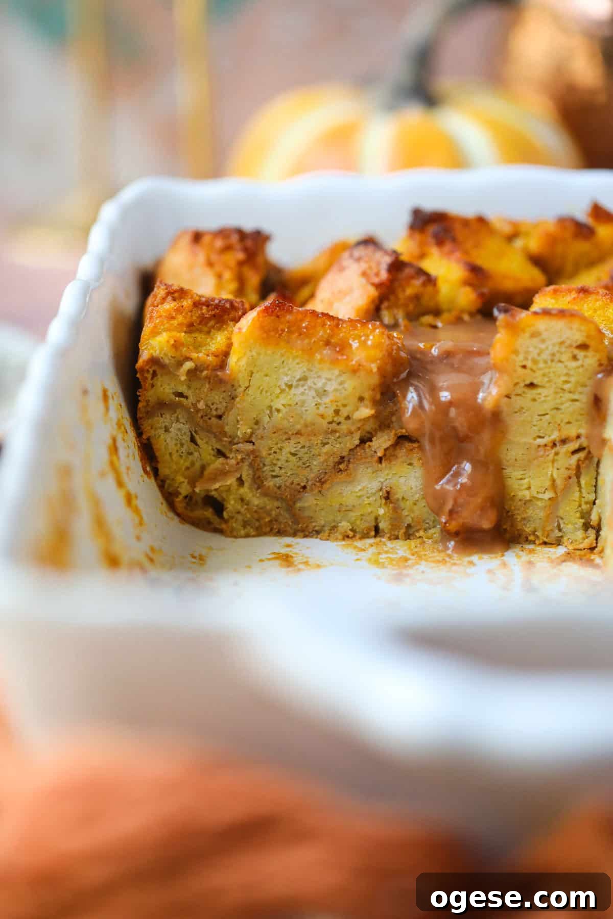 Salted Caramel Pumpkin Bread Pudding Recipe 7 Pumpkin bread pudding with salted caramel sauce that has been sliced in a white baking dish.
