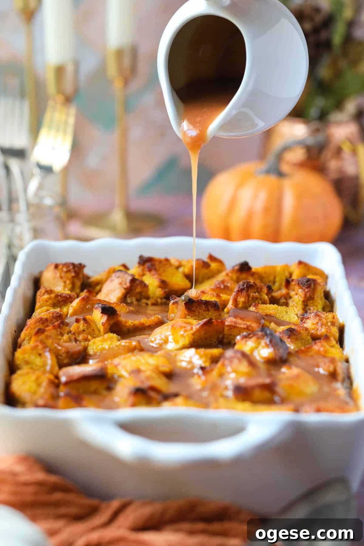 Salted Caramel Pumpkin Bread Pudding Recipe 8 Pumpkin bread pudding in a white baking dish with salted caramel sauce being poured over top.