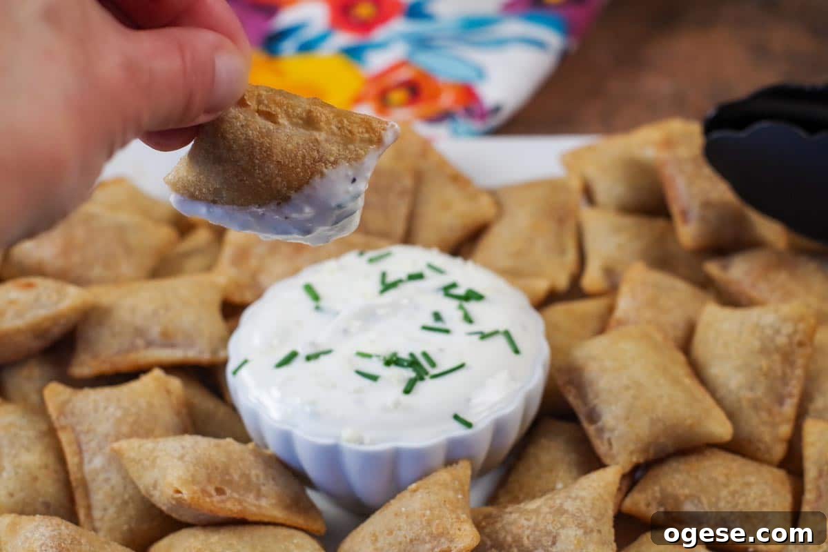 Crispy Air Fryer Pizza Bites with Tangy Dipping Sauce 2 air fryer pizza bite being dipped over a tray of more air fryer pizza bites
