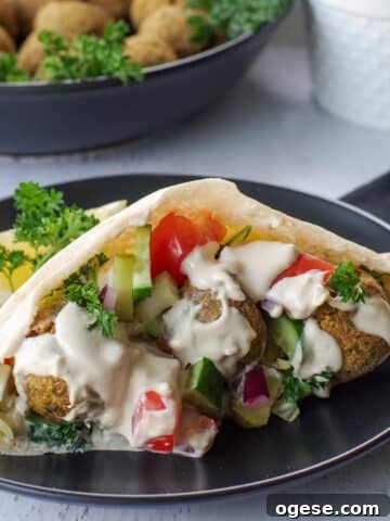 air fryer falafel pita on a black plate with a bowl of falafel balls in the background