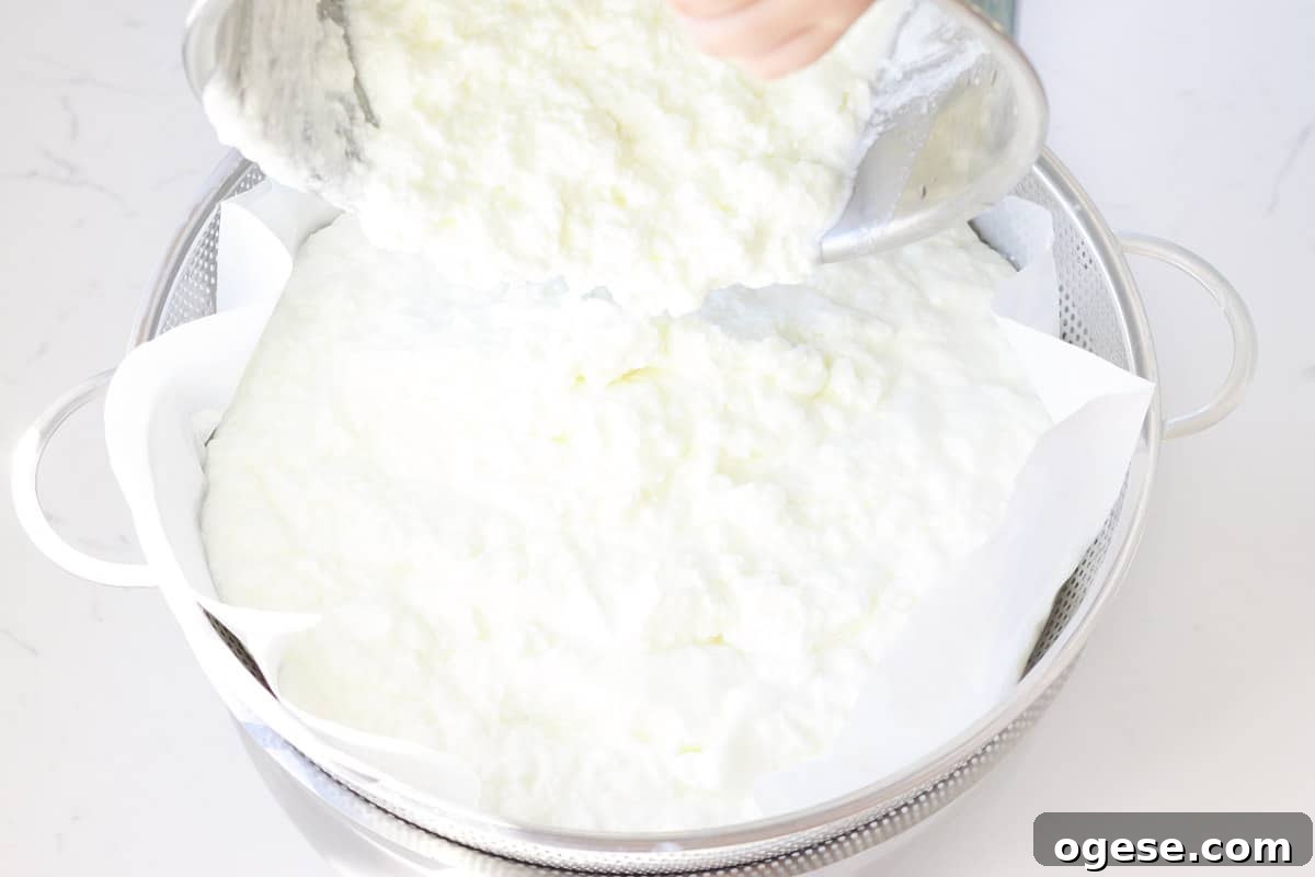 homemade yogurt being poured into a colander lined with coffee filters
