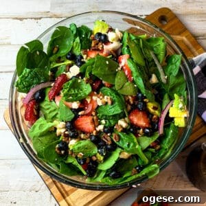 Strawberry spinach salad in a clear bowl drizzled with balsamic vinegar dressing.