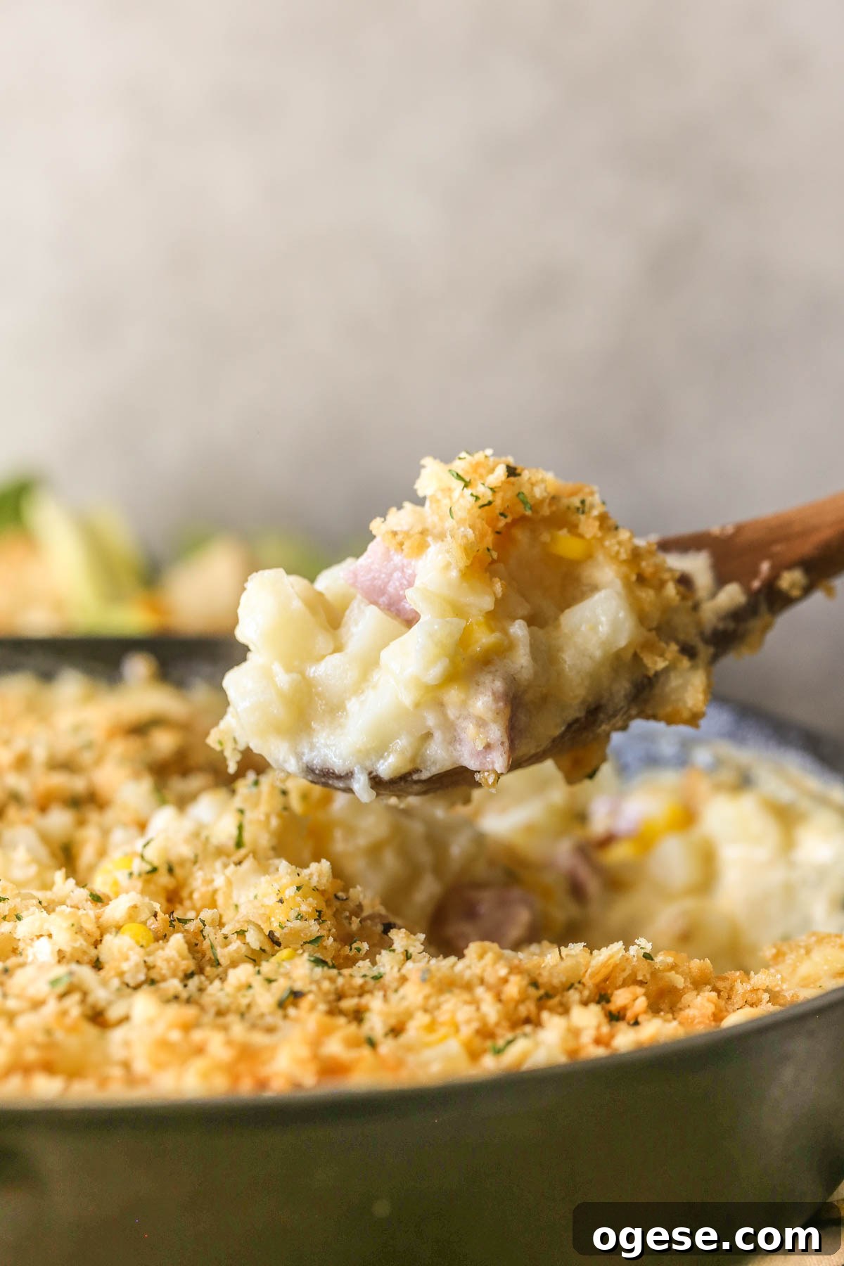 Cheesy Ham & Potato Skillet Recipe for Comforting Weeknight Meals 3 Close up shot of a wooden spoon full of Cheesy Ham and Potato Skillet, held above the cast iron skillet.