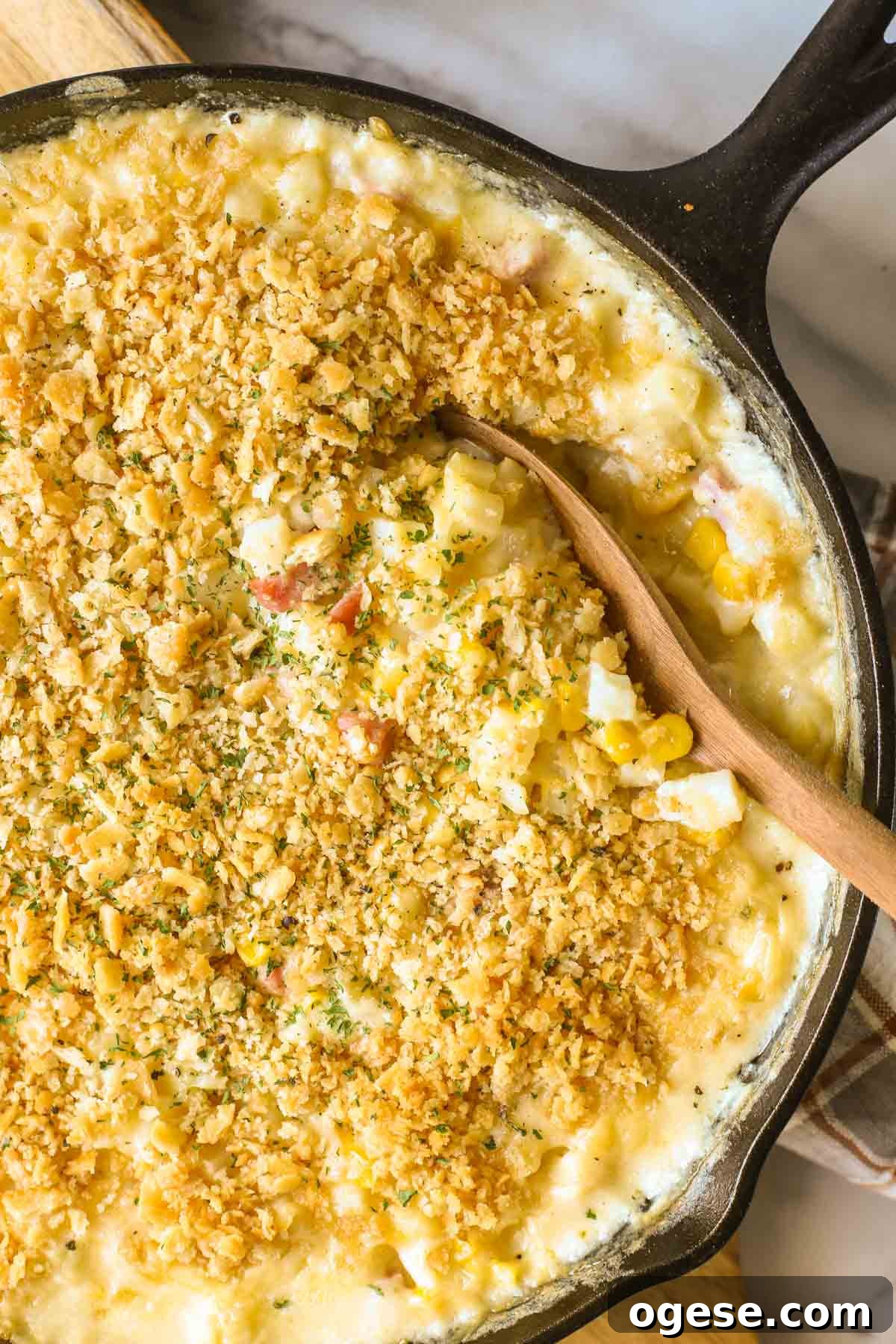 Cheesy Ham & Potato Skillet Recipe for Comforting Weeknight Meals 4 Close up overhead shot of Cheesy Ham and Potato Skillet in a cast iron skillet with a wooden serving spoon in it.