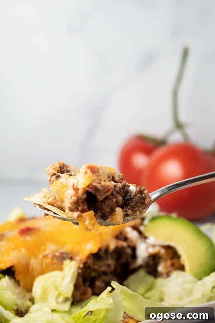 Low-Carb Taco Casserole with Cheesy Cauliflower Crust 13 spoon full of beef held up in front of keto taco casserole with lettuce and avocado