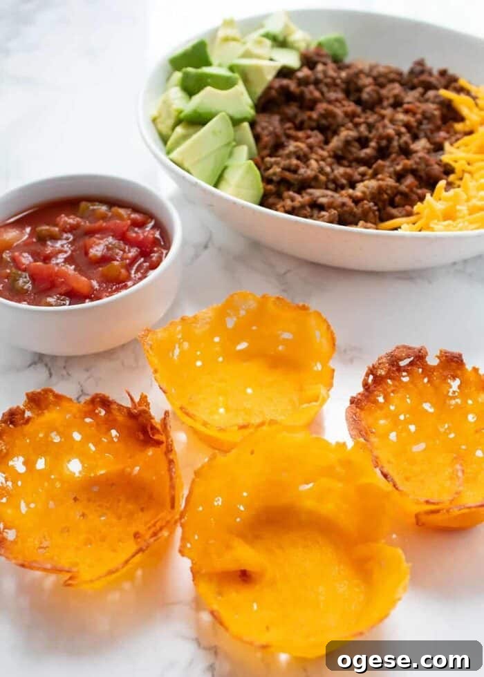 Low-Carb Taco Casserole with Cheesy Cauliflower Crust 9 keto taco cups with salad and taco ingredients in background