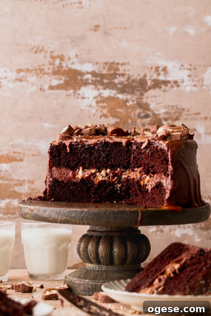 Decadent Twix Bar Cake Recipe with Caramel and Chocolate 3 Side view of twix cake on a cake stand.