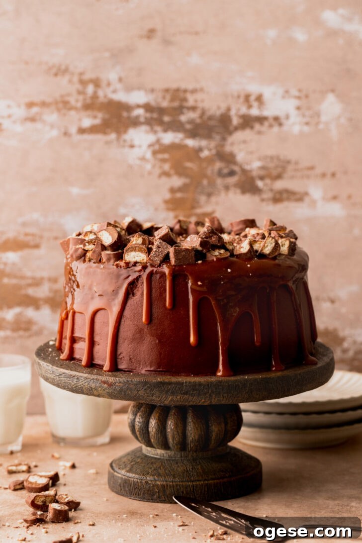 Decadent Twix Bar Cake Recipe with Caramel and Chocolate 9 Decorated cake on a cake stand.