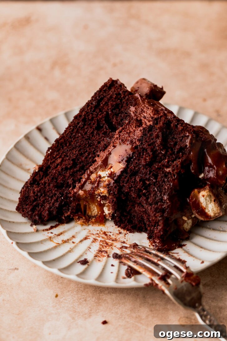 Decadent Twix Bar Cake Recipe with Caramel and Chocolate 10 Bite missing from piece of cake on a plate.