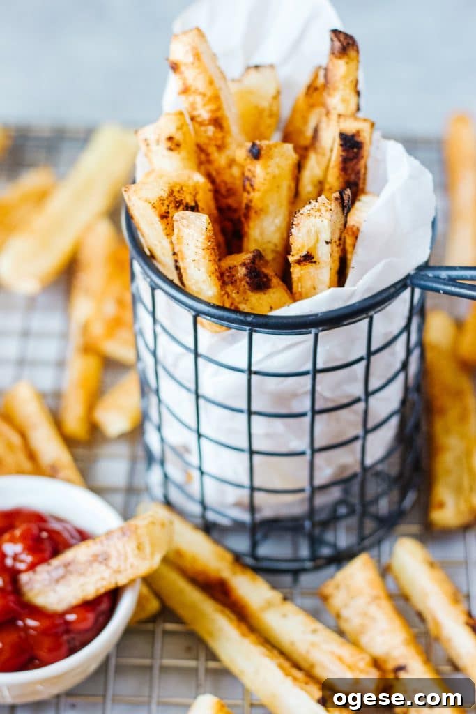 Crispy Baked Yuca Fries Recipe for Perfect Crunch 2 Slices of baked yuca in a cooling rack and in a wire mesh container with a small container of ketchup and a small piece of the fries in it