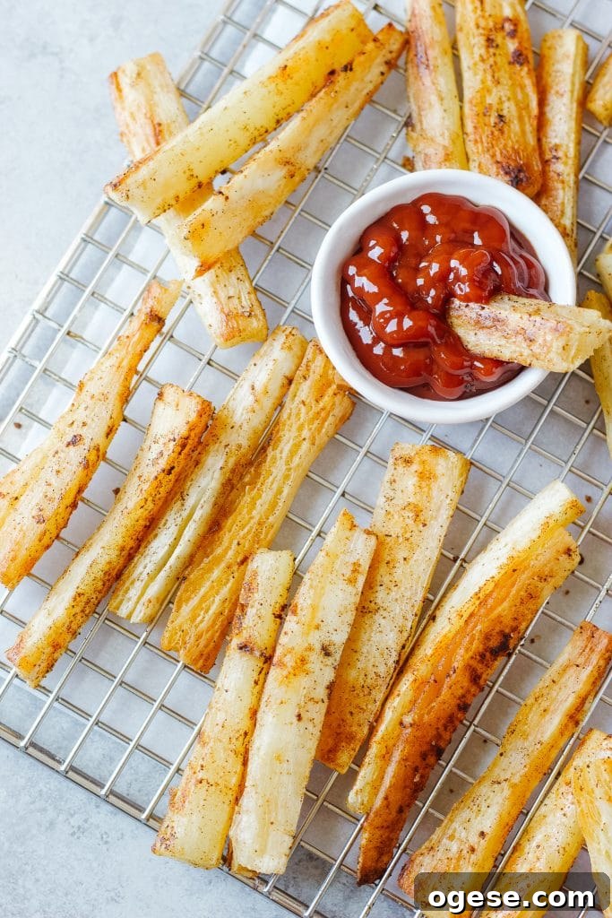 Crispy Baked Yuca Fries Recipe for Perfect Crunch 3 A small bowl with ketchup and slices of the yuca root baked and cooled in a cooling rack.