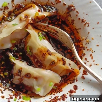 Dumplings are served over wet wet sauce in a white bowl.