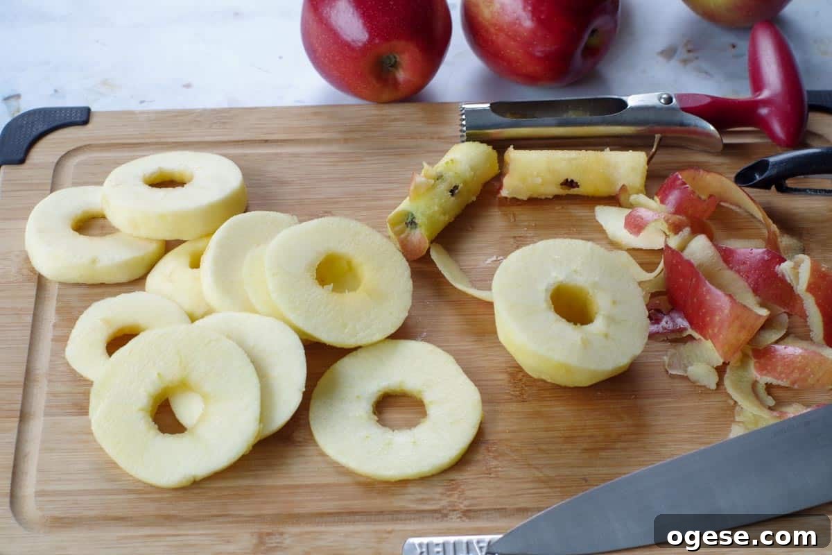 Air Fryer Dried Apples: Simple Step-by-Step Dehydrating Guide 4 apples peeled, cored and cut into about 3mm circles on cutting board, with corer and knife and peels in background