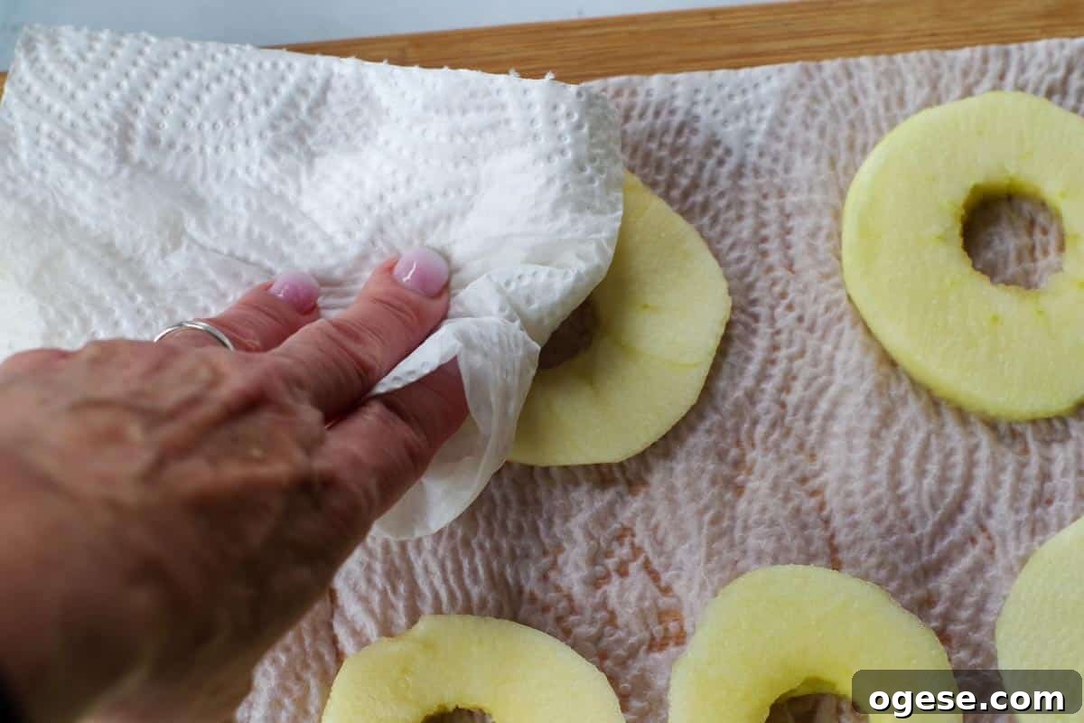 Air Fryer Dried Apples: Simple Step-by-Step Dehydrating Guide 6 apples being patted dry with paper towel