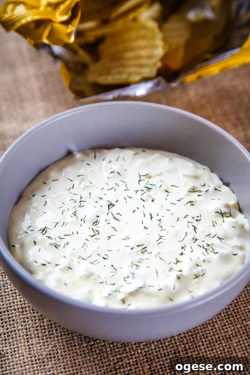 Creamy Dill Pickle Dip Recipe for Parties and Snacks 4 a bowl of dill pickle dip sprinkled with fresh dill.