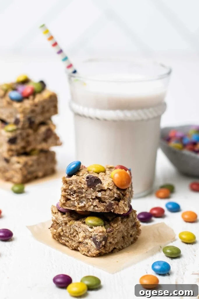 Chewy Monster Cookie Bars with M&Ms and Peanut Butter 2 Stacks of cookies surrounding a glass of milk.