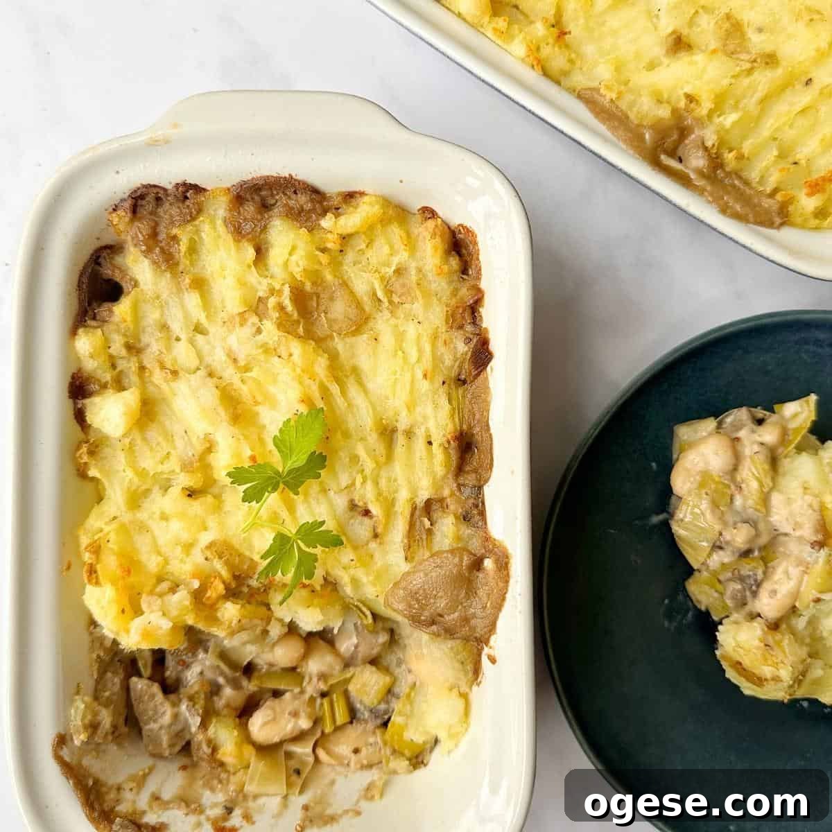 Vegan Mushroom Pie in a baking dish and blue plate on a white marble background.