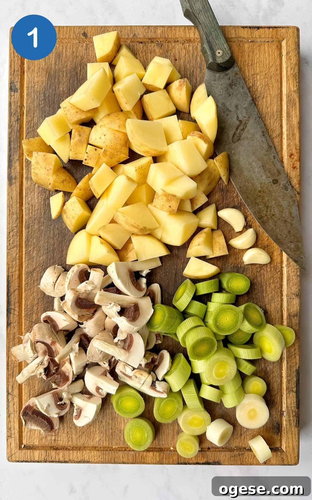 Chopped potatoes, mushrooms and leeks on a wooden chopping board.