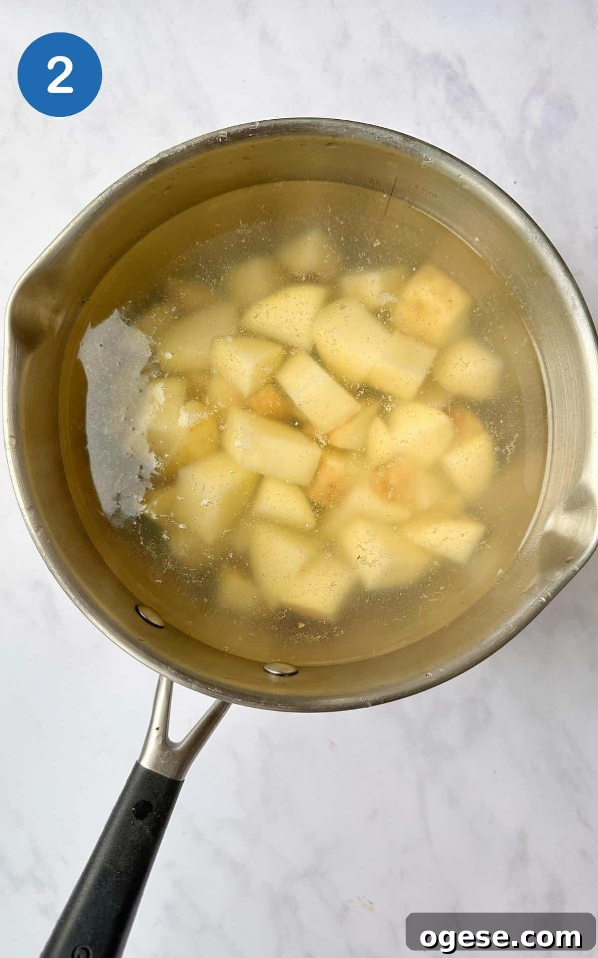 Chopped potatoes boiling in a saucepan.