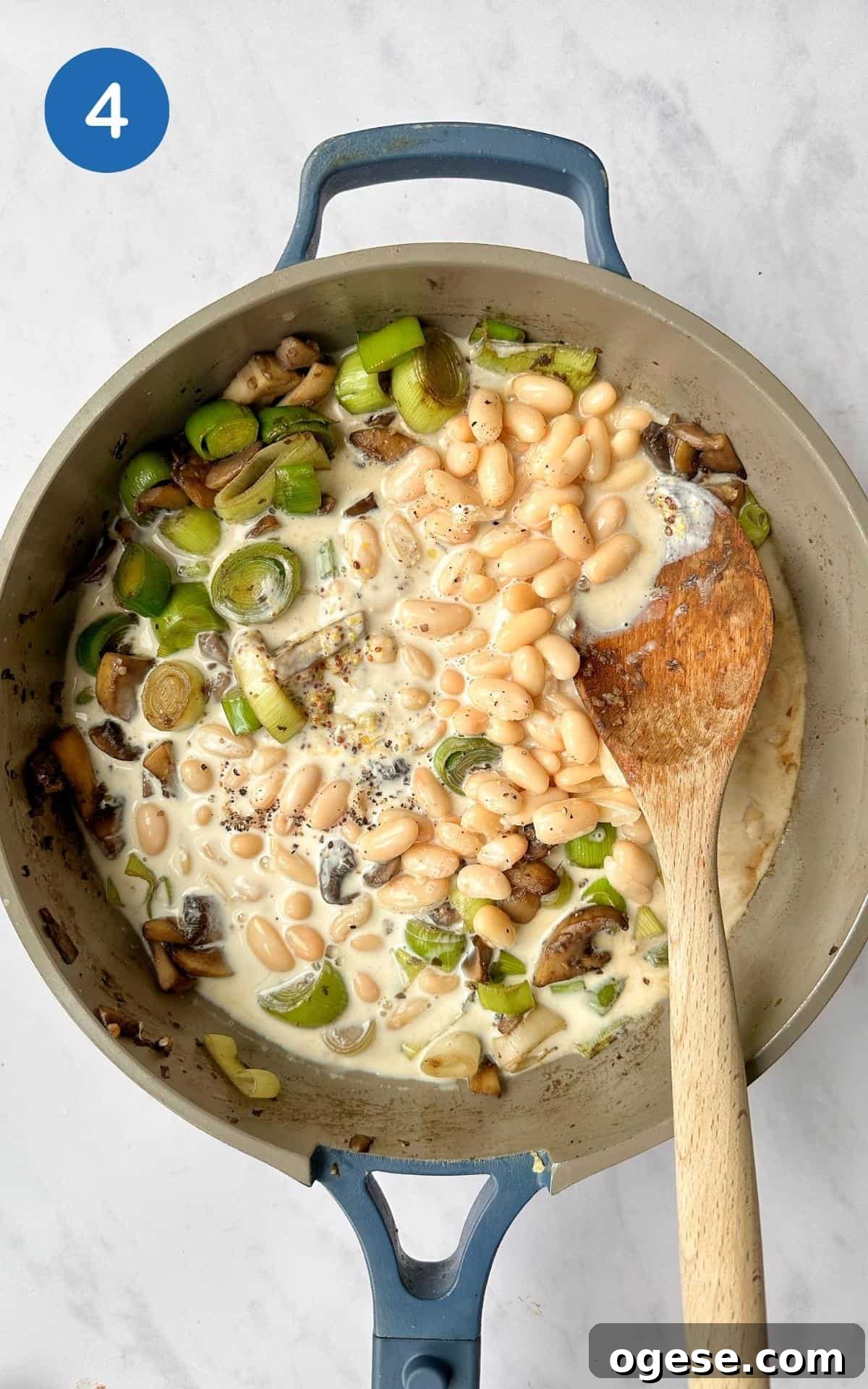 Mushrooms, leeks, cannellini beans and soya cream simmering in a non-stick frying pan.