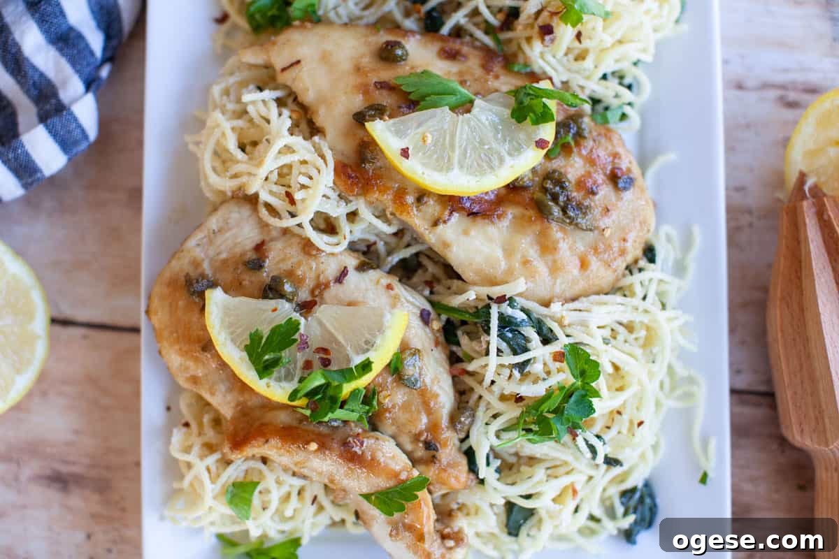 overhead of chicken piccata topped with lemon slices and parsley on a bed of pasta