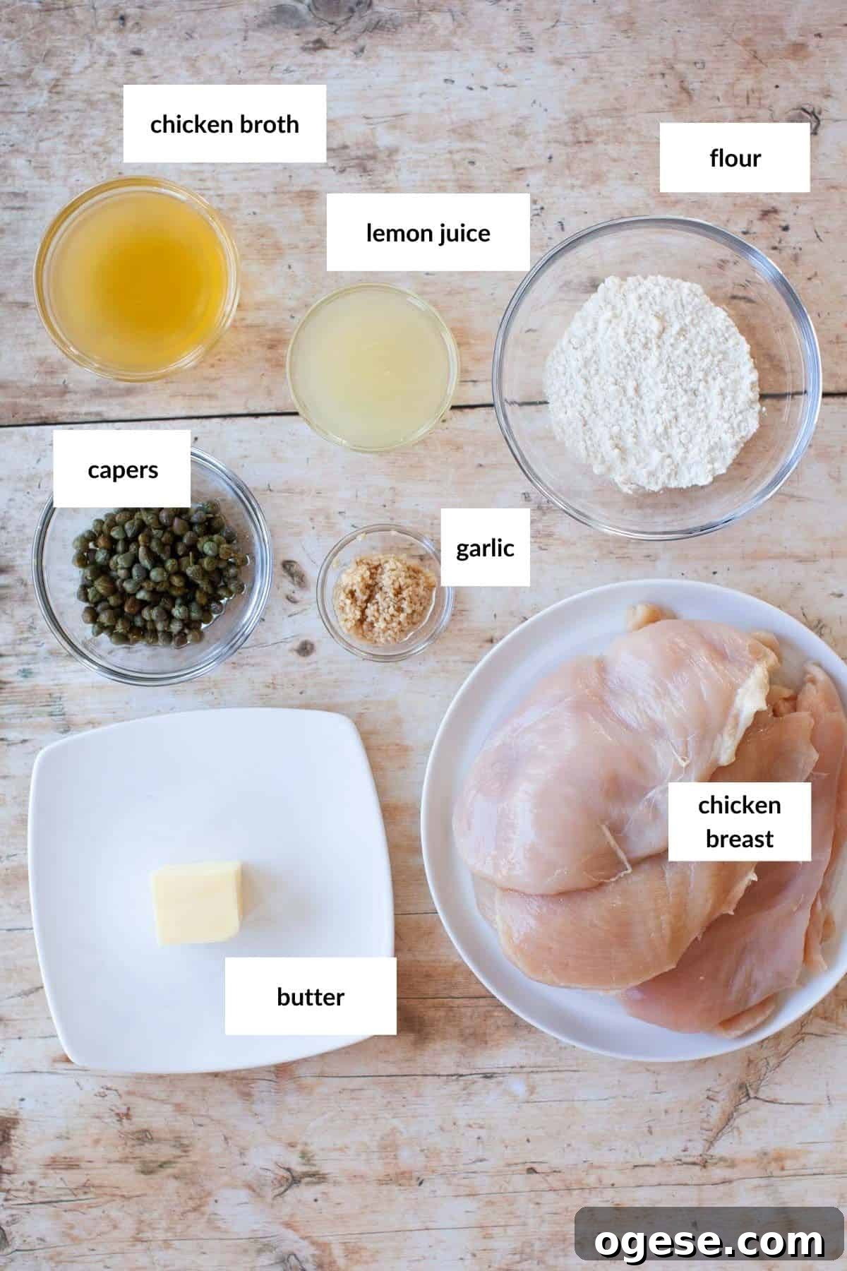 A plate with uncooked chicken breasts, with bowls of ingredients around it on a wooden surface.